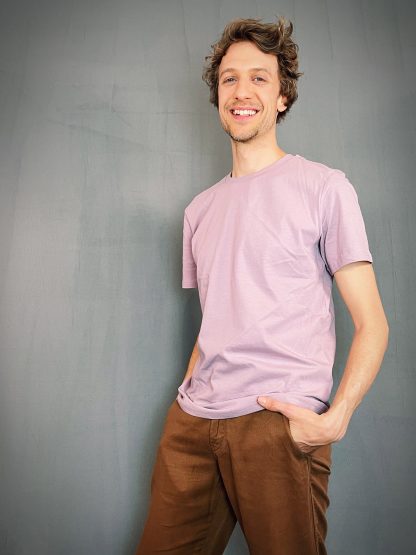 Natürlicher fröhlicher Kerl trägt ein gerade geschnittenes unisex T-shirt in einem pastellfarbenen lila Farbton.